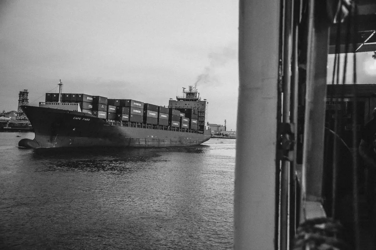 A cargo ship loaded with containers moving through a harbor