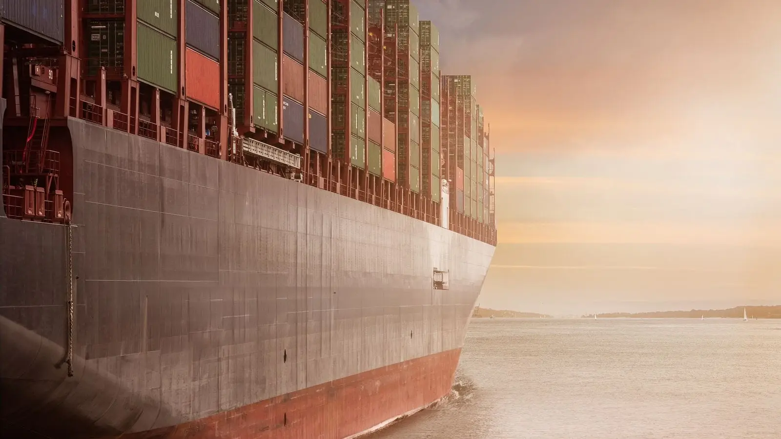 A large container vessel under way, fully loaded, at sunset