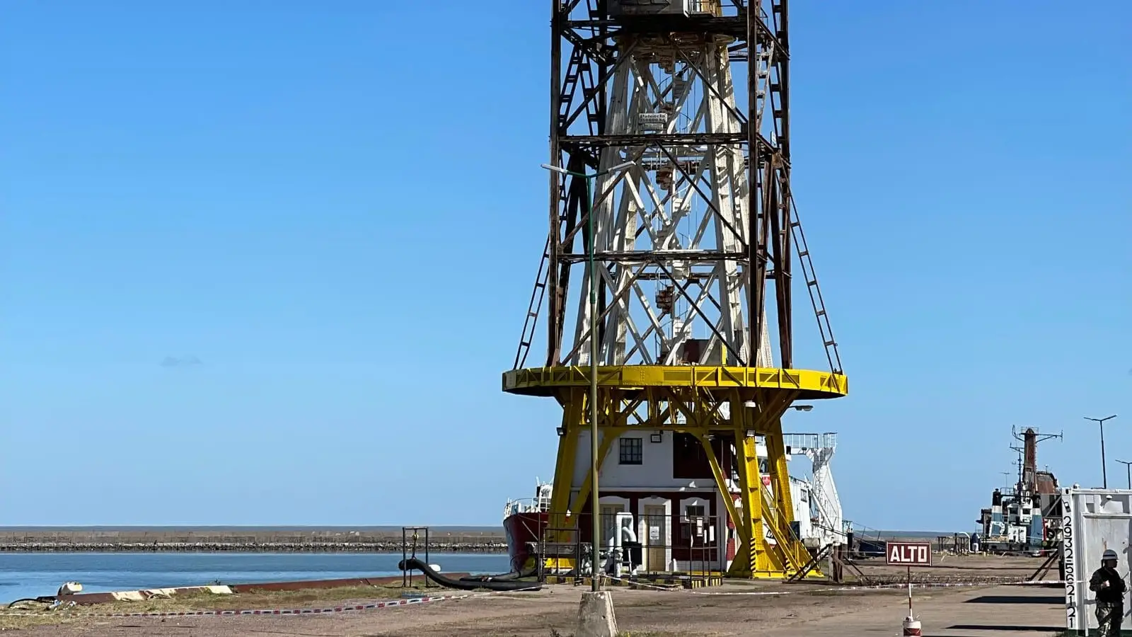 A yellow dockside crane on a cargo pier against a clear sky