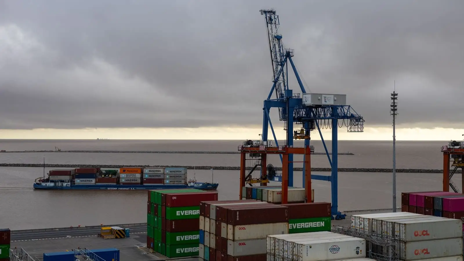 Quayside cranes above stacked shipping containers at a commercial terminal