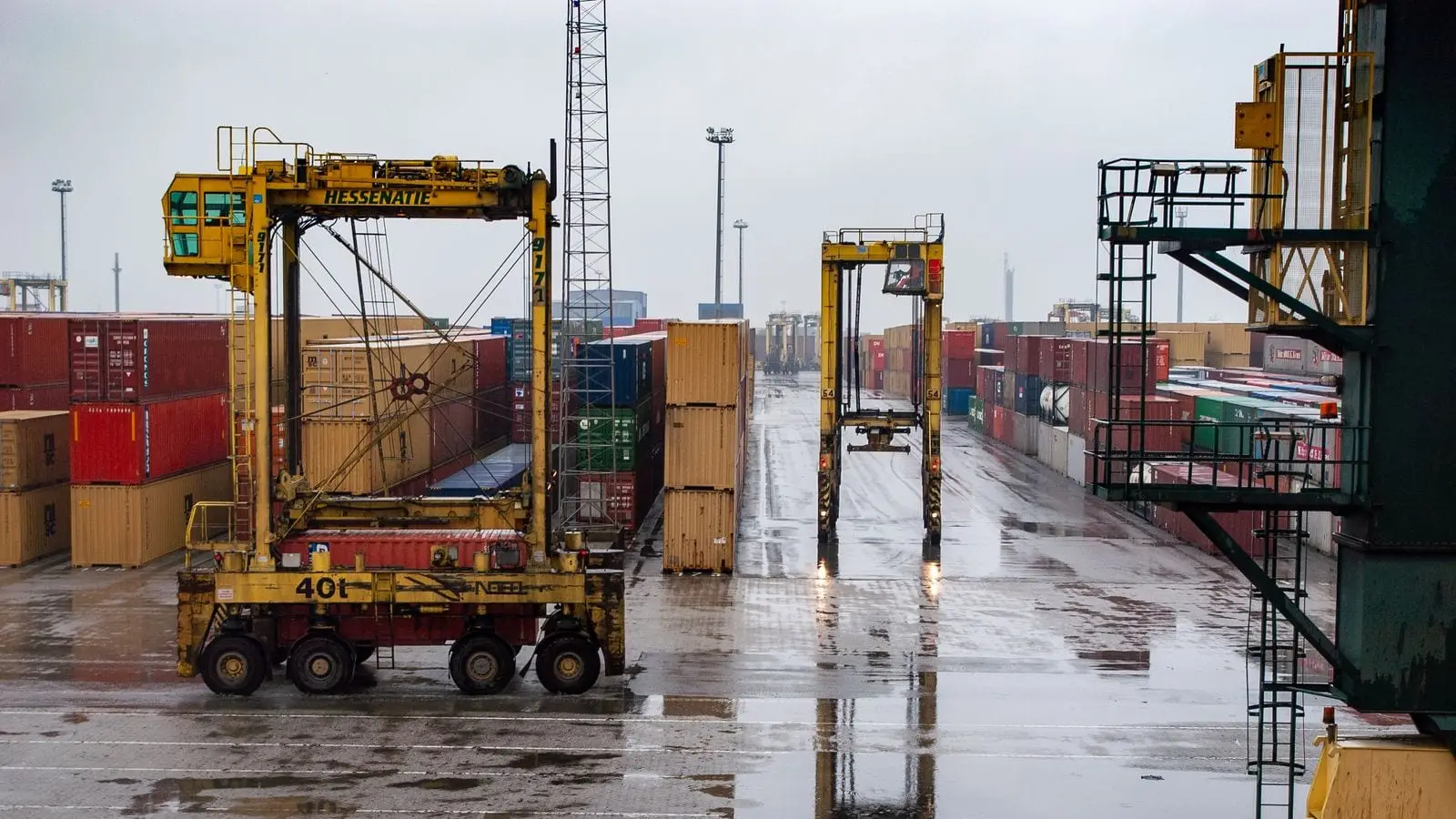 Straddle carriers moving between rows of containers in a terminal yard