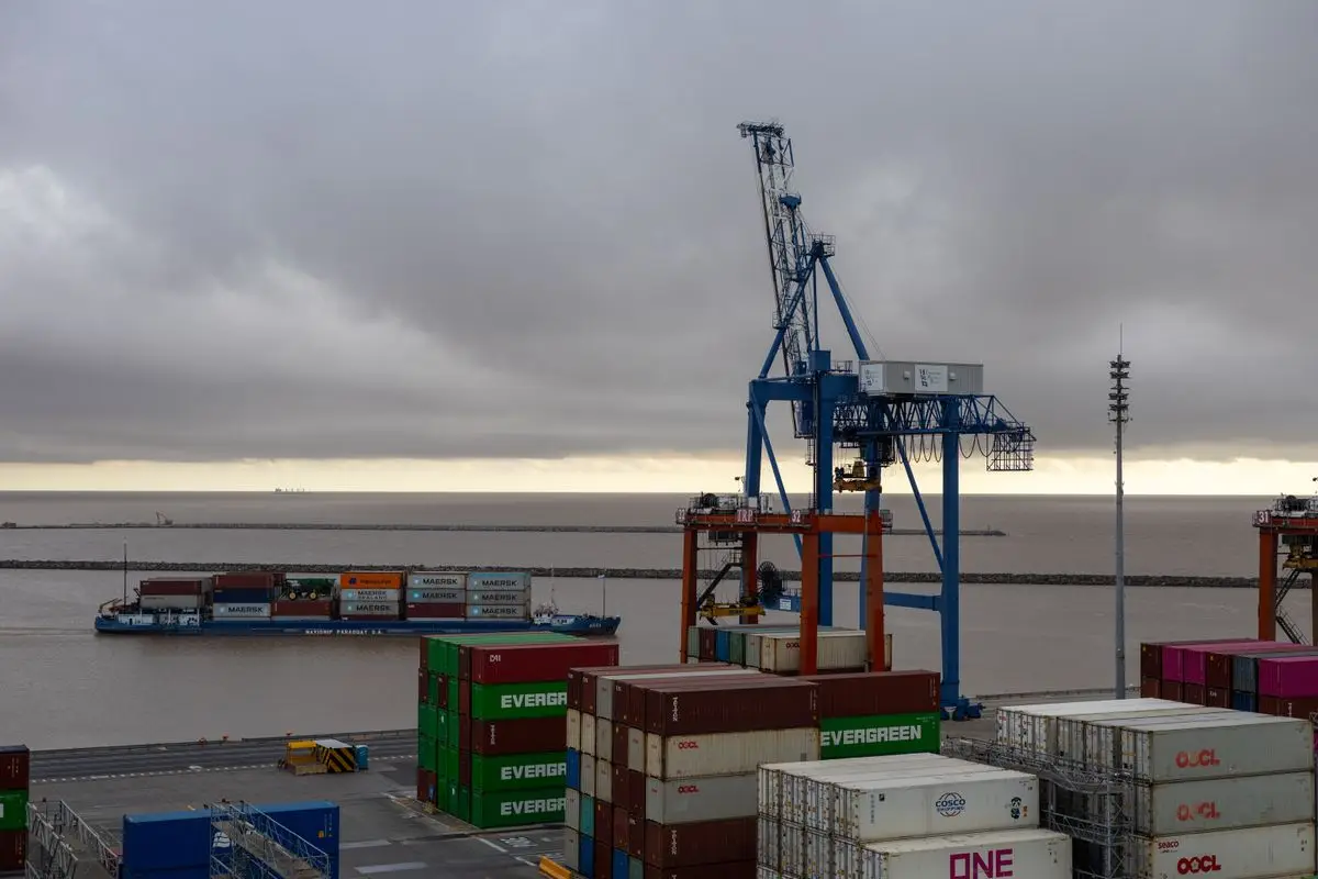 Cargo cranes and stacked shipping containers at a commercial port terminal