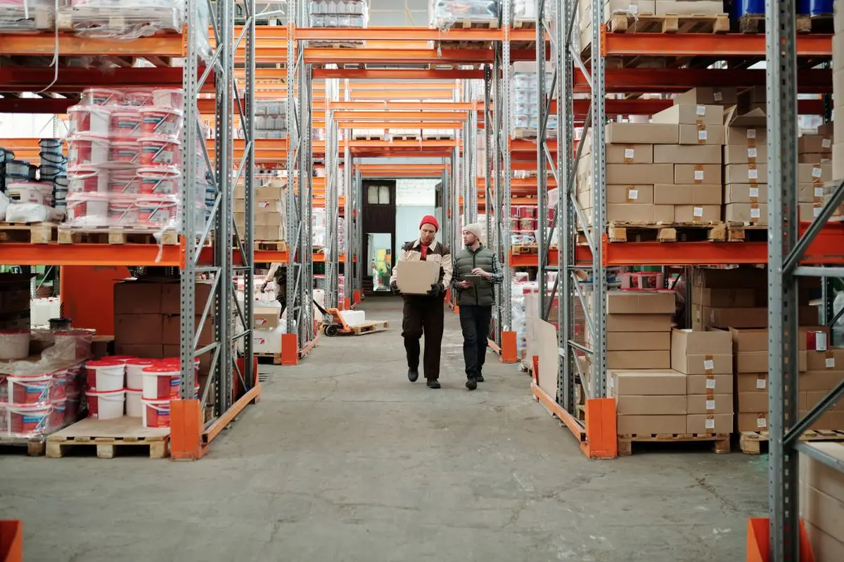 Warehouse staff handling packages among storage shelving